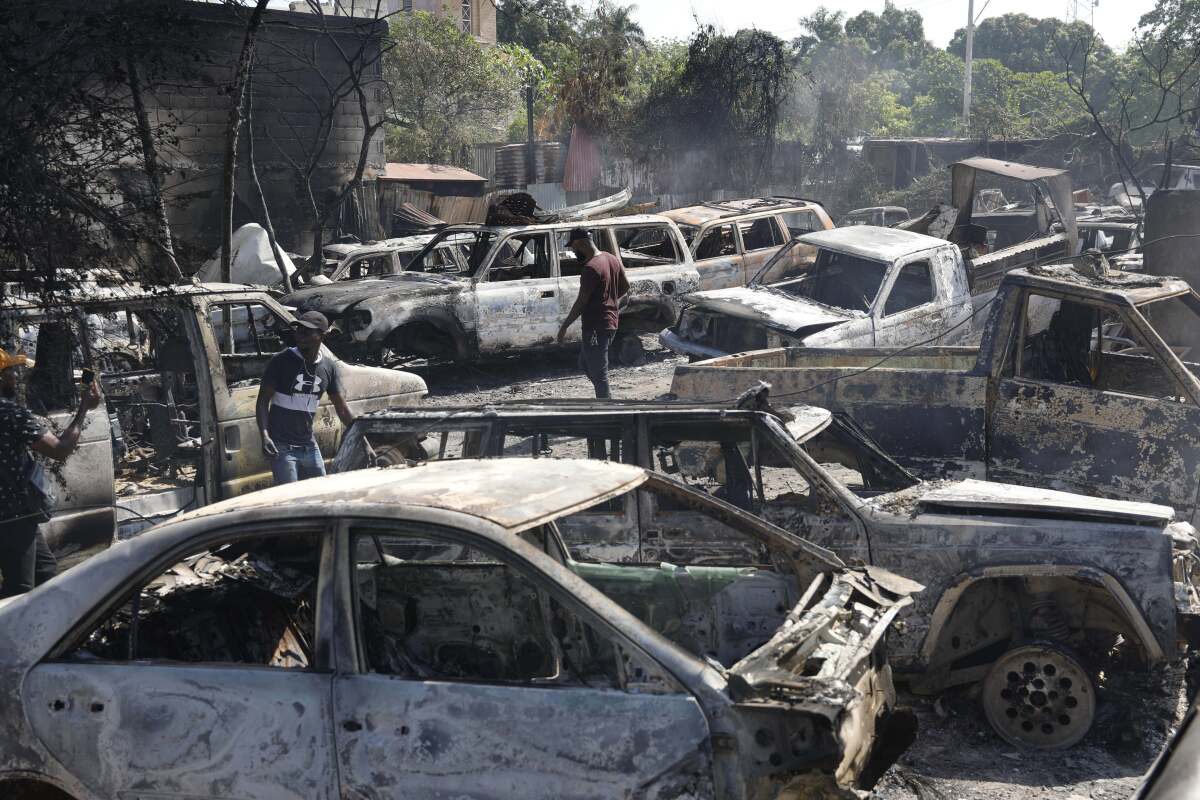 People look for salvageable pieces from burned cars at a mechanic shop in Port-au-Prince, Haiti.