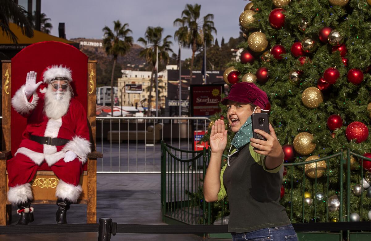 A shopper takes a socially distanced selfie with Santa Claus. 