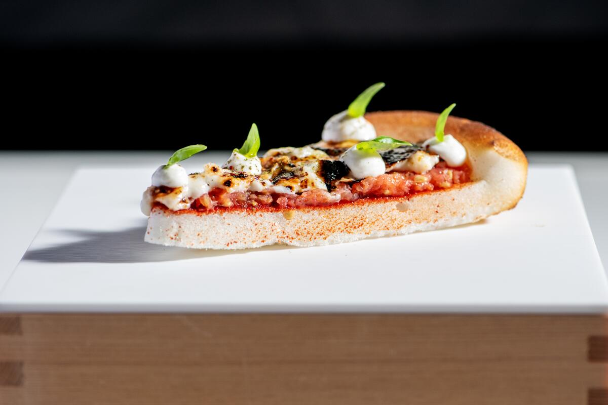 Pizza margherita, made from powdered egg whites and tomato water and dolloped with mozzarella mousse.