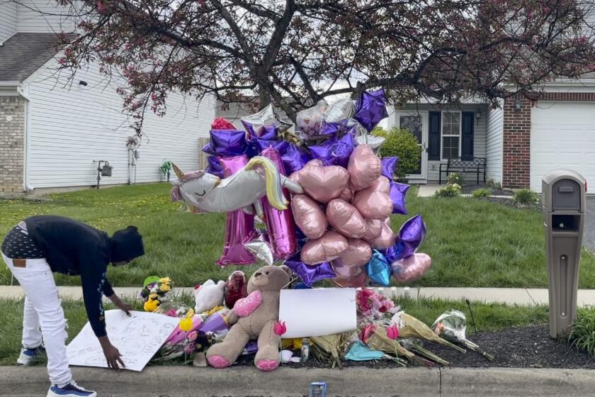 A man adjusts a sign near a memorial at the scene in the Columbus, Ohio neighborhood Friday, April 23, 2021 where 16-year-old Ma'Khia Bryant was fatally shot by police as she swung at two other people with a knife on Tuesday, April 20. Three Democratic members of Congress are asking the U.S. Department of Health and Human Services to investigate the foster care circumstances leading up to the fatal police shooting of Bryant. U.S. Rep. Joyce Beatty and Sen. Sherrod Brown of Ohio, along with Oregon Rep. Ron Wyden, penned a letter Tuesday, June 1, 2021 on behalf of Bryant’s parents, requesting for the federal agency to look into the teen’s experience through the foster care system. (AP Photo/Farnoush Amiri)