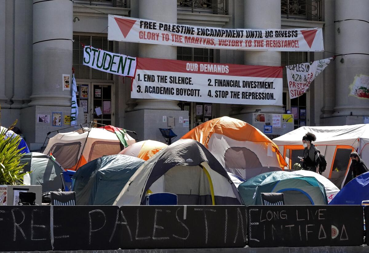 A banner above tents at UC Berkeley lists "Our Demands," including "Financial Divestment."