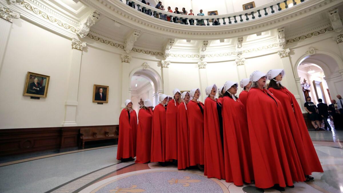 Activists dressed as characters from "The Handmaid's Tale" chant in the Texas Capitol Rotunda as they protest a bill requiring healthcare facilities to bury or cremate remains from abortions, miscarriages and stillbirths. (Eric Gay / Associated Press)