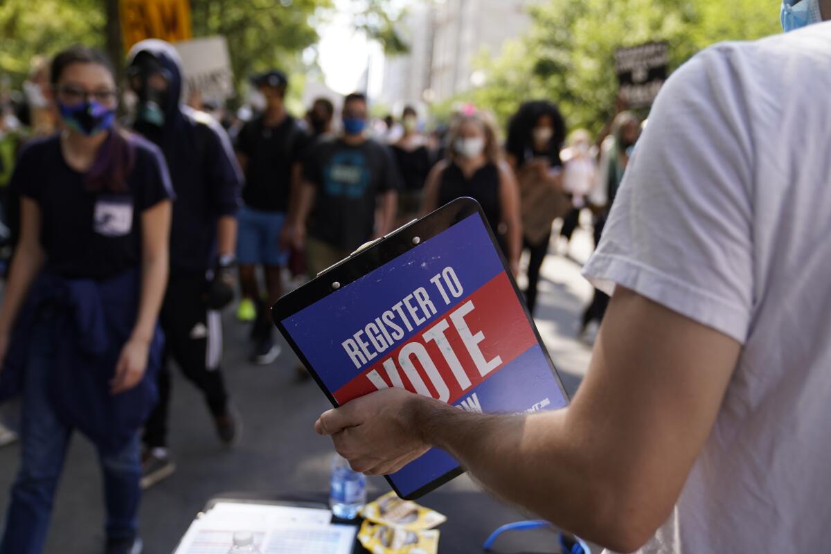 An activist holds a clipboard asking passersby to register to vote during a protest in Washington in June 2020.