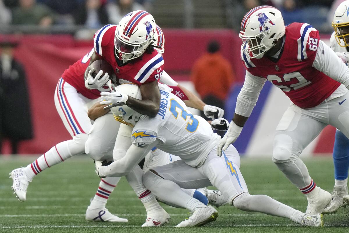 Patriots running back Rhamondre Stevenson takes a hit from Chargers safety Derwin James Jr. (3).