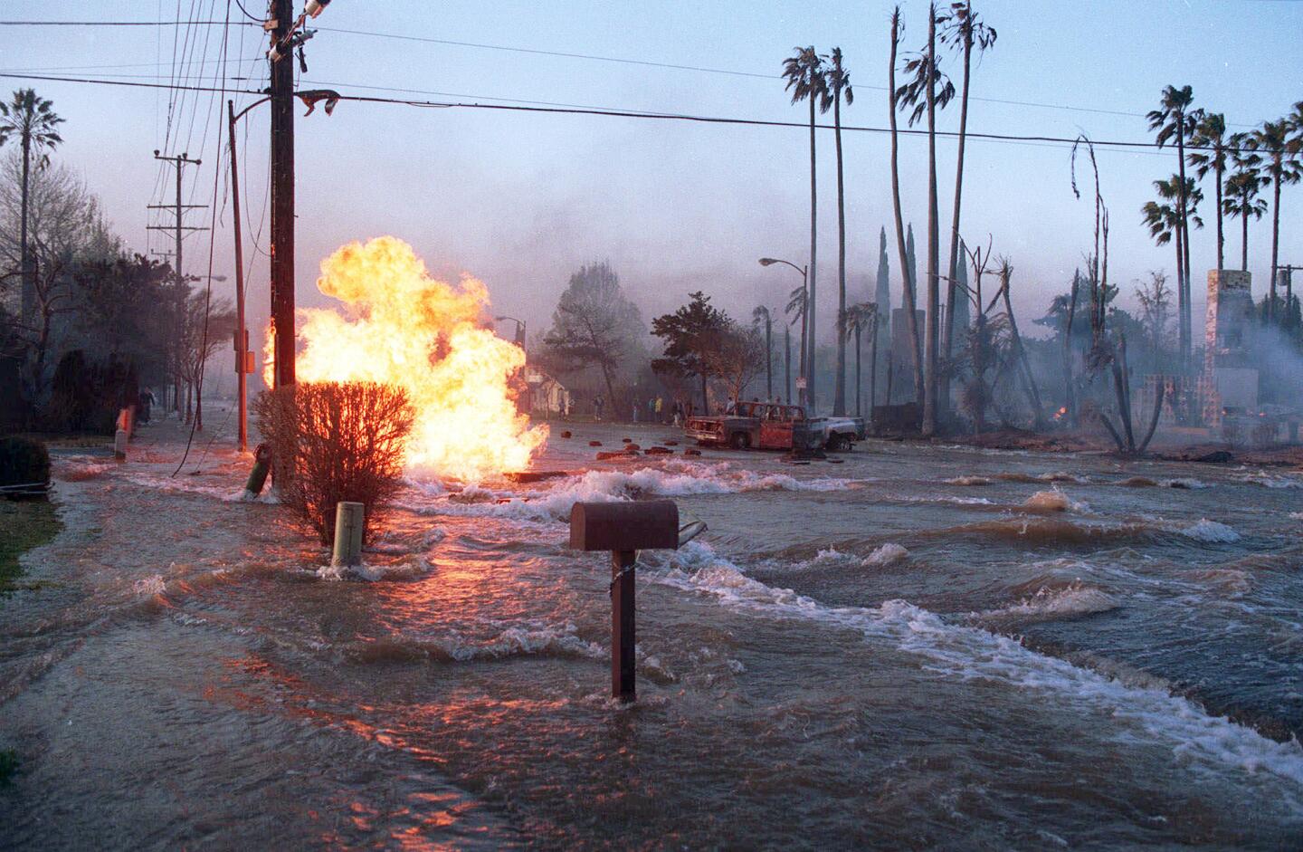 Gas from a ruptured supply line burns as water from a broken water main floods Balboa Boulevard in the Granada Hills area of Los Angeles. The fire from the gas main destroyed two homes, right.