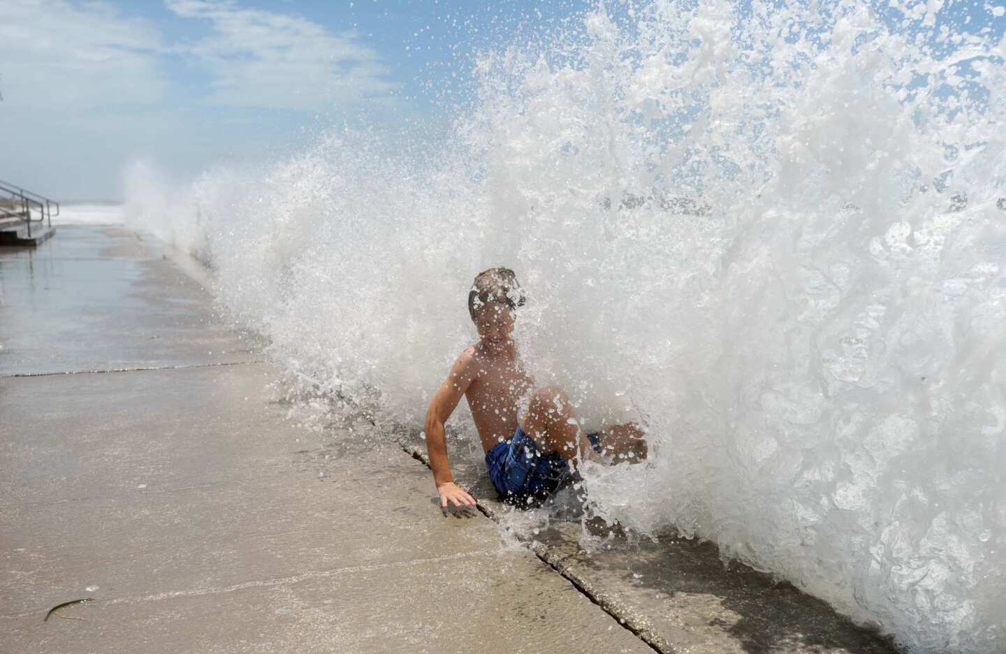 Maxi Kluzek, 8, enjoys the rough weather as waves slam into the seawall in Pass-a-Grille, Fla.