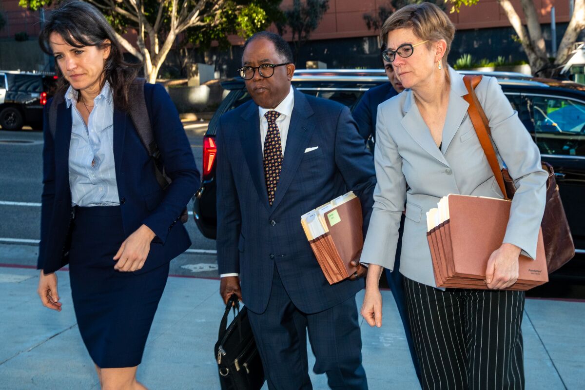 Three people in suits walk carrying files