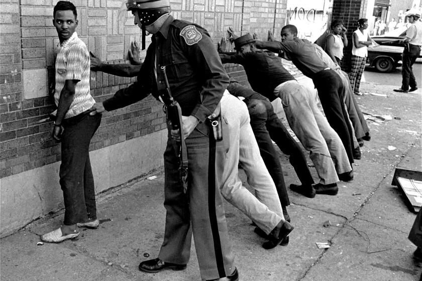 FILE - In this July 24, 1967 file photo, a Michigan State police officer searches a youth on Detroit's 12th Street where looting was still in progress after the previous day's rioting. The last surviving member of the Kerner Commission says he remains haunted that the panel's recommendations on US race relation and poverty were never adopted, but he is hopeful they will be one day. Former U.S. Sen. Fred Harris says 50 years after working on a report to examine the causes of the late 1960s race riots he strongly feels that poverty and structural racism still enflames racial tensions even as the United States becomes more diverse. (AP Photo/File)