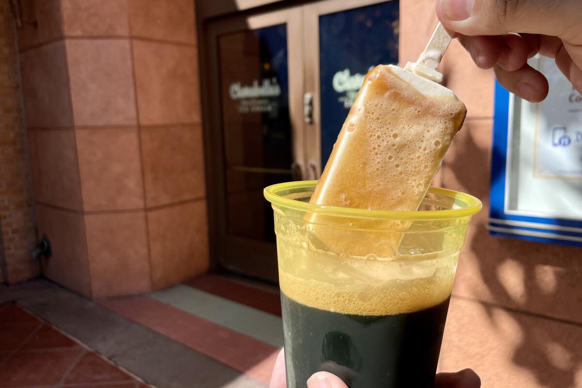 A vanilla ice cream bar dipped in a plastic cup of Guinness beer