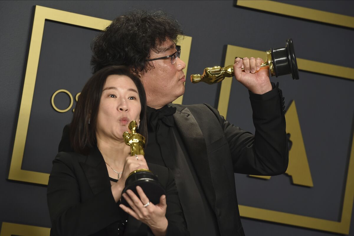 Producer Kwak Sin Ae, left, and director Bong Joon Ho pose in the press room Sunday at the Oscars after their best picture win.