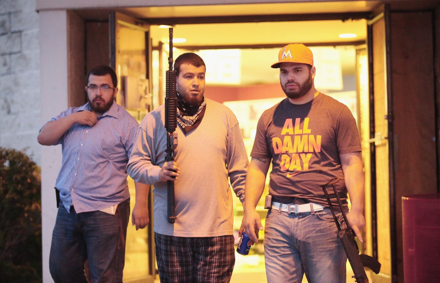 Men carry rifles to protect a grocery store in Ferguson after a new outbreak of vandalism and looting.