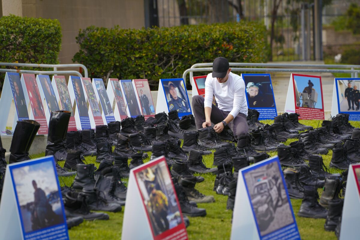 A volunteer sets out 200 pairs of boots, representing 600 San Diego police and firefighters who oppose the vaccine mandate.