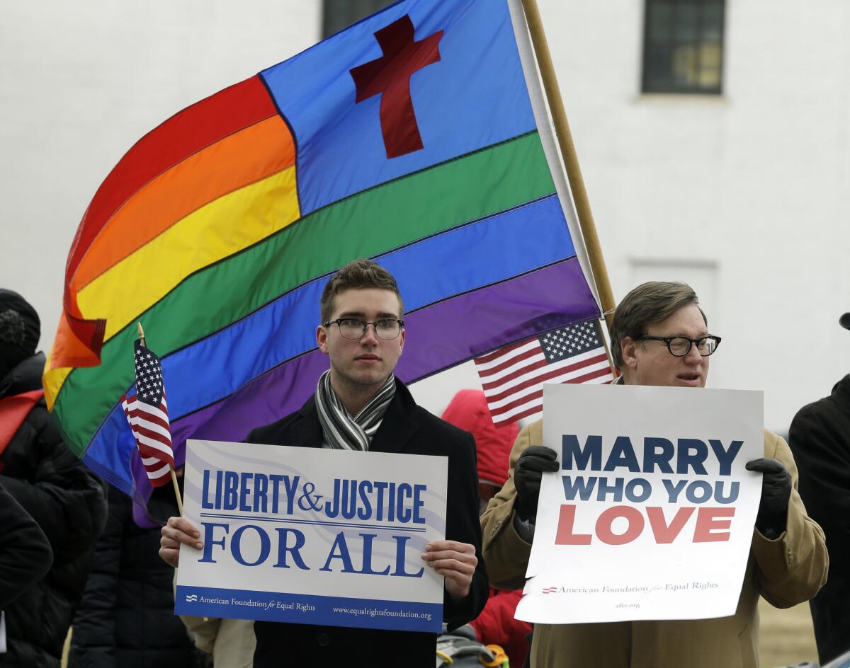 In this Feb. file photo, Spencer Geiger, left, of Virginia Beach, and Carl Johanson, of Norfolk, hold signs as they demonstrate outside Federal Court in Norfolk, Va. A new poll shows that acceptance is growing for same-sex marriage.