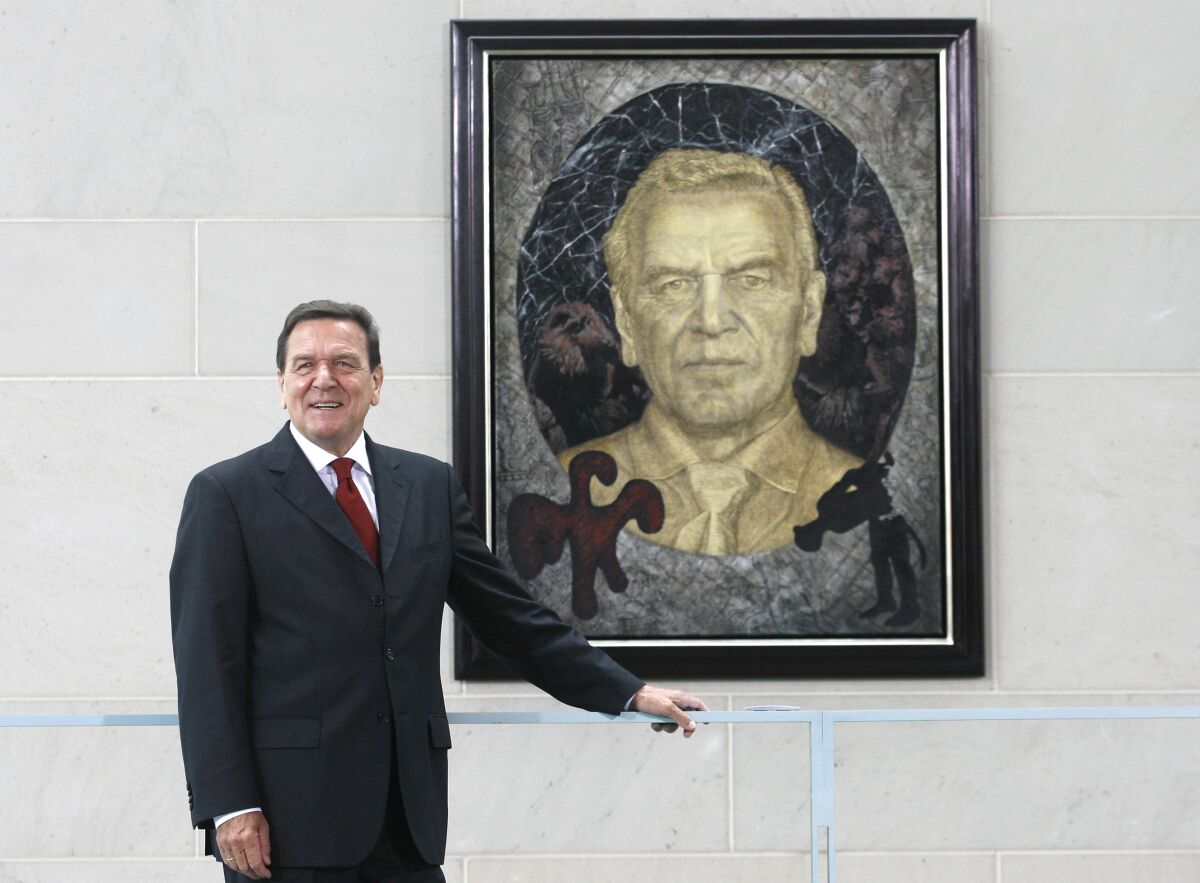 FILE - Former German Chancellor Gerhard Schroeder poses in front of a painting by German artist Joerg Immendorff in the chancellery in Berlin on Tuesday, July 10, 2007. Germany's three governing parties plan to strip former Chancellor Gerhard Schroeder of his office and staff after he maintained and defended his long-standing ties with Russia despite the war in Ukraine. (AP Photo/Markus Schreiber, File)