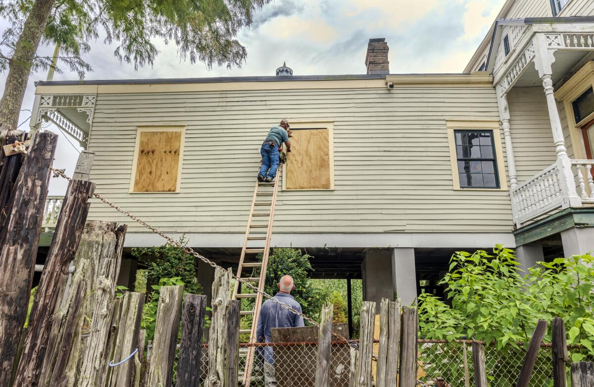 The windows of a raised historic house are boarded up in Lafitte, La.