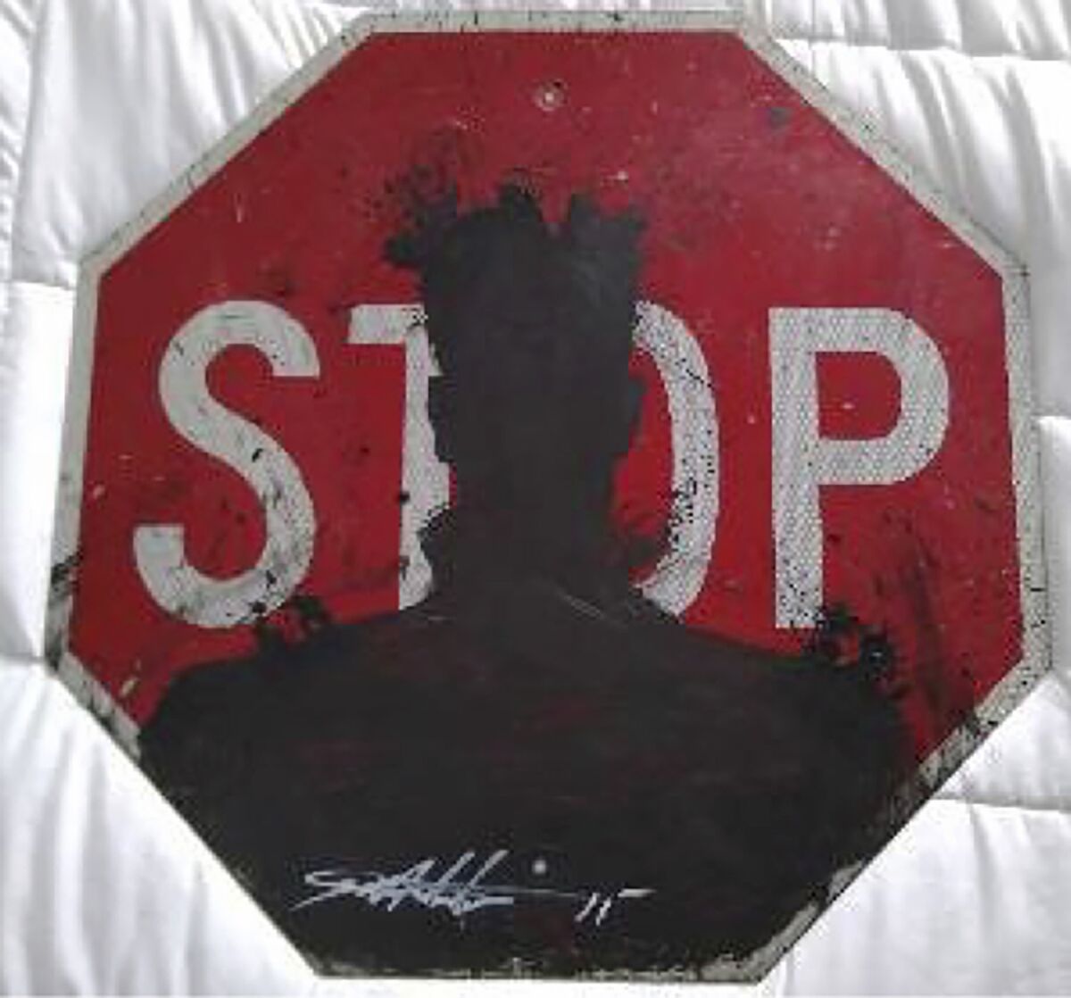 A shadow figure head and shoulders painted on a stop sign in the style of Richard Hambleton
