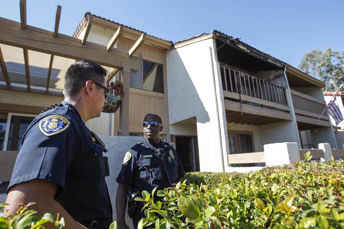 Dos policías de San Diego se paran frente a un condominio quemado, a la derecha, donde dos niños pequeños murieron luego de ser rescatados del incendio de la madrugada del sábado en Rancho Bernardo. El padre de los niños resultó gravemente herido, pero se espera que sobreviva.