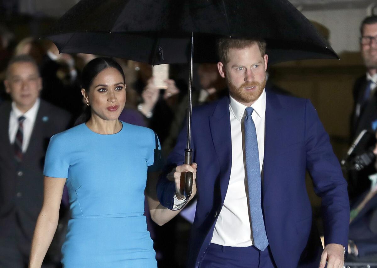 Meghan and Prince Harry walking with an umbrella