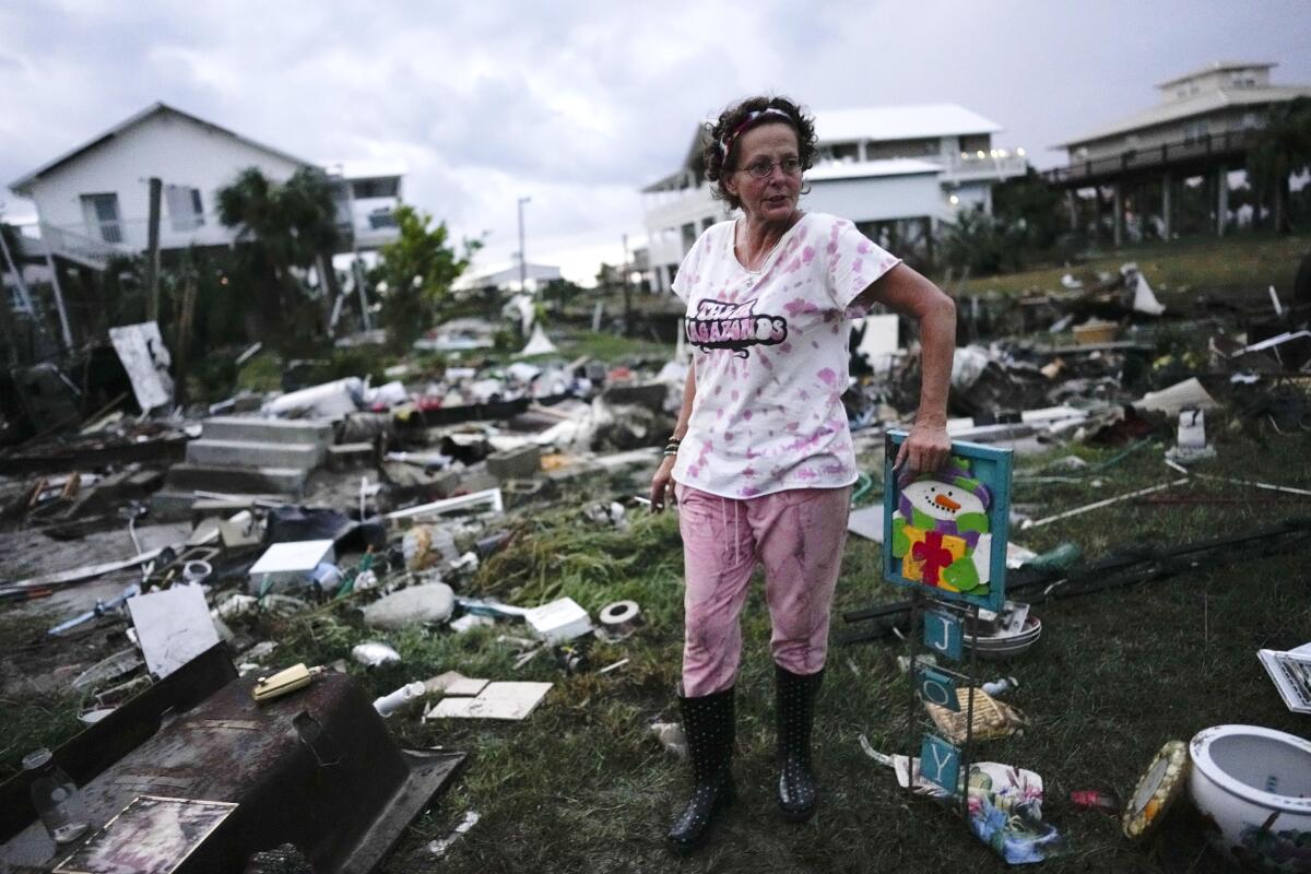 Woman standing amid debris of her mother’s home after Hurricane Idalia