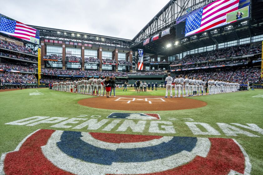 The Philadelphia Phillies and Texas Rangers stand for the national anthem before an opening day baseball game, Thursday, March 30, 2023, in Arlington, Texas. (AP Photo/Jeffrey McWhorter)
