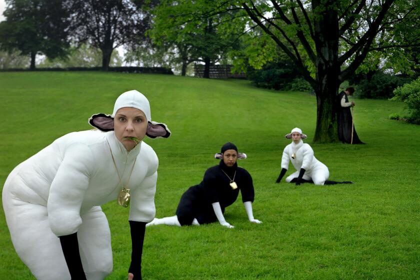 Three actors dressed as sheep in a grassy field.