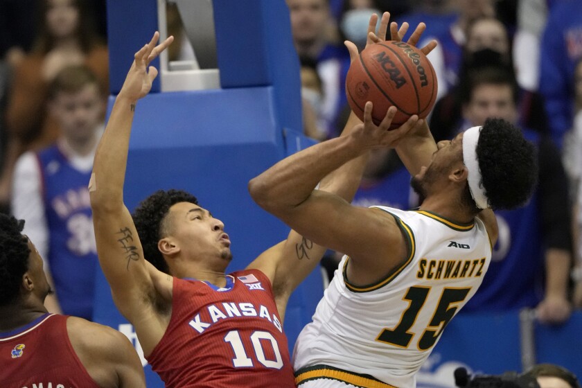 George Mason guard D'Shawn Schwartz (15) shoots over Kansas forward Jalen Wilson (10) during the first half of an NCAA college basketball game in Lawrence, Kan., Saturday, Jan. 1, 2022. (AP Photo/Orlin Wagner)