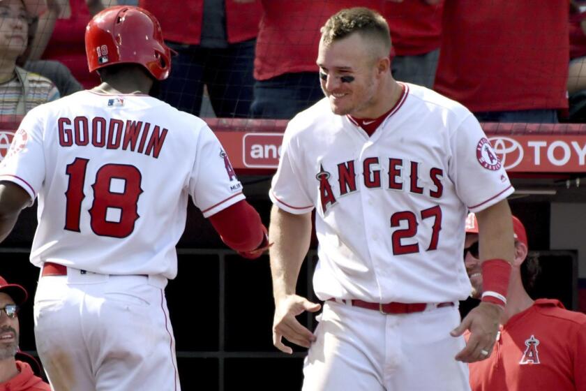 Los Angeles Angels' Brian Goodwin (18) is greeted at the dugout by Mike Trout after hitting a solo home run during the seventh inning against the Texas Rangers in a baseball game Sunday, April 7, 2019, in Anaheim, Calif. (AP Photo/Michael Owen Baker)