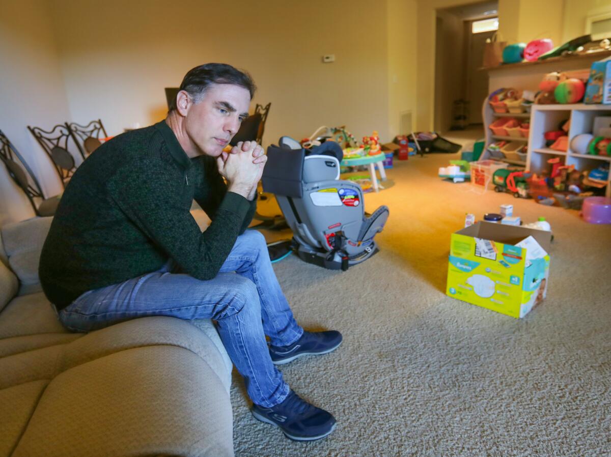 Ken Burnett sits in the living room of his San Diego apartment full of toys belonging to his son, Rowan Burnett, 3, and daughter, Mia Burnett, 1. His wife, Yanjun Wei, and their children are stuck in Wuhan, China, because of the coronavirus outbreak.