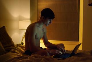 A man types on his laptop in bed.