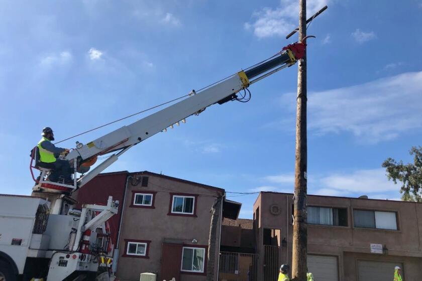 A San Diego Gas & Electric crew removes the last above-ground utility pole on L Street between 20th and 21st streets in the Sherman Heights neighborhood of San Diego.