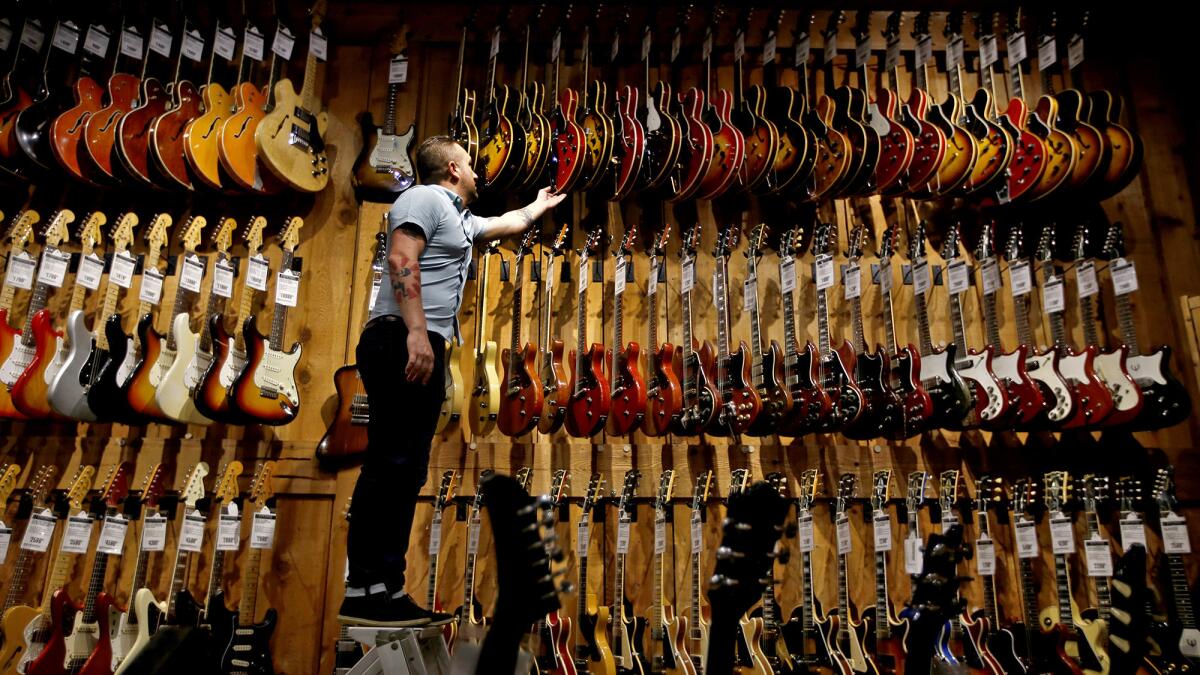 Patrick Carpenter looks at guitars at the Guitar Center in Hollywood in 2017.