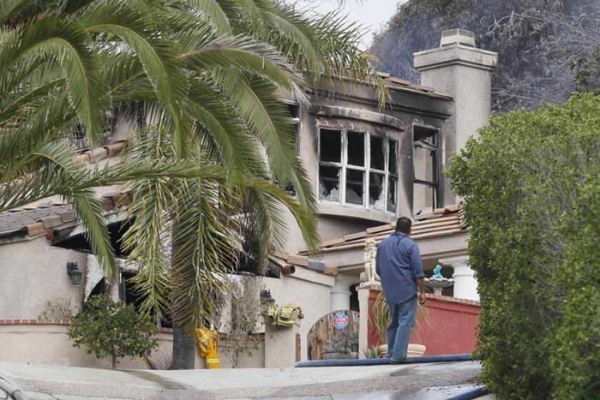 Sheriff Bomb Arson investigators comb through a hillside home in Encinitas that was heavily damaged in an early morning two-alarm fire that killed one person.