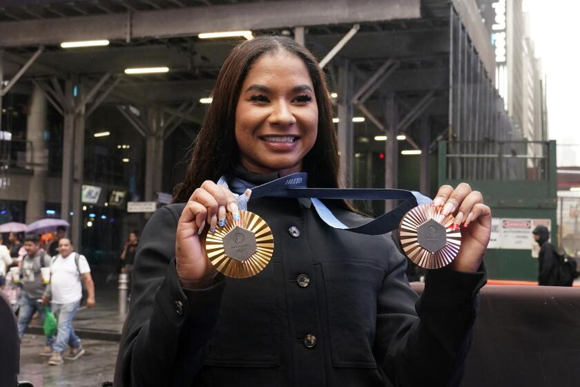 La gimnasta estadounidense y medallista olímpica Jordan Chiles muestra sus medallas tras el cierre del Nasdaq MarketSite, en Times Square, Nueva York, el jueves 8 de agosto de 2024. (AP Foto/Richard Drew)