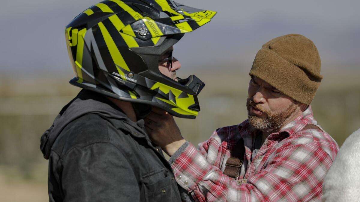 Ben Stone, right, helps Daniel Noll put on a safety helmet before he ventures out in a Polaris vehicle.