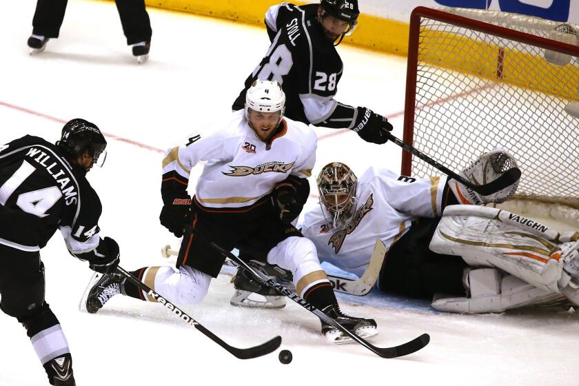 Kings right wing Justin Williams takes a shot against Ducks defenseman Cam Fowler and goalie John Gibson as teammate Jarret Stoll positions himself next at the crease in the second period.