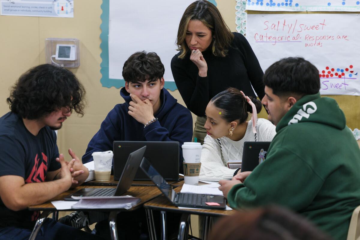 San Gabriel High School teacher Leah Ruiz stands behind four seated students with laptops. 