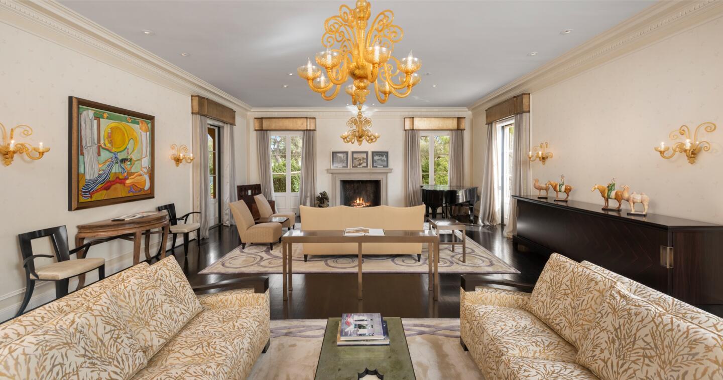 A rectangular room with two sitting areas, a fireplace and a chandelier.