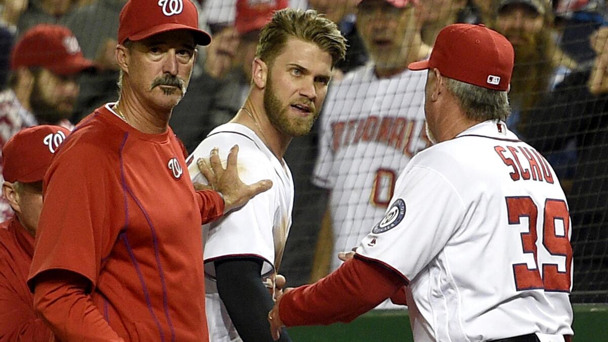 Nationals outfielder Bryce Harper, center, is restrained by hitting coach Rick Schu (39) and pitching coach Mike Maddux after getting ejected from a game Monday night.
