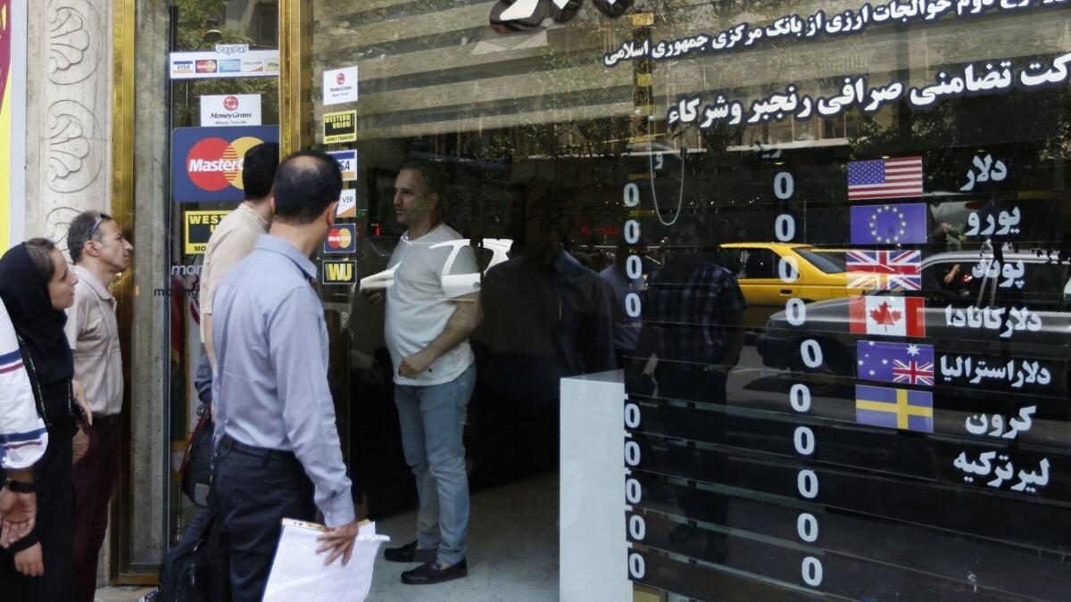 People check currency exchange rates in front of a shop in Tehran on Aug. 8, 2018.