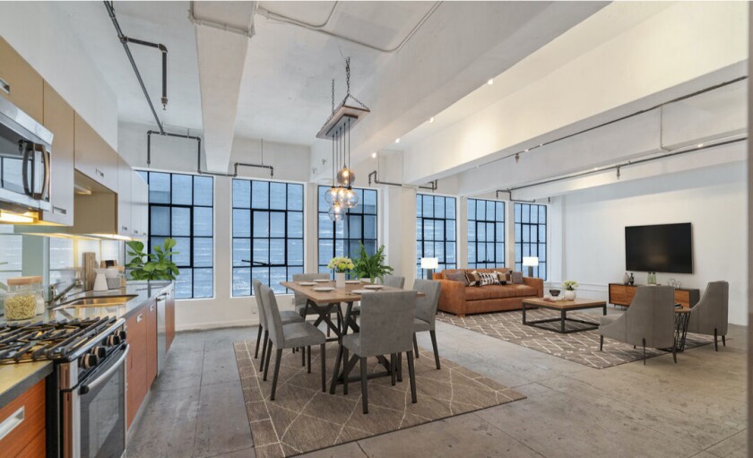 A loft in downtown Los Angeles includes an open layout kitchen, dining table and living room.