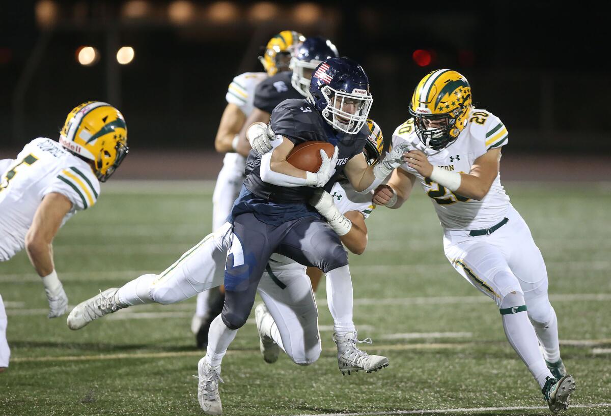 Newport Harbor running back Justin McCoy (3) runs for a first down as Edison's Jeremy Alcorn and Trent Fletcher (20) bring him down in a Sunset League game on Thursday.