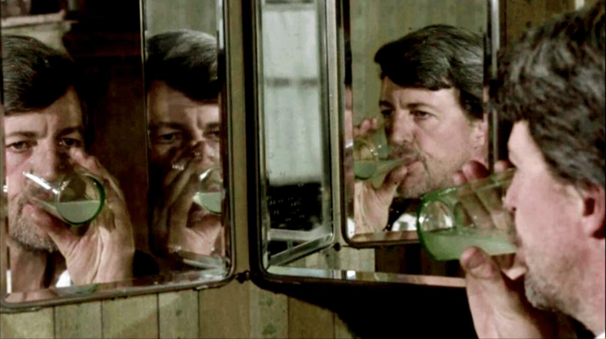 Reflected multiple times in a mirror, a man drinks from a glass.