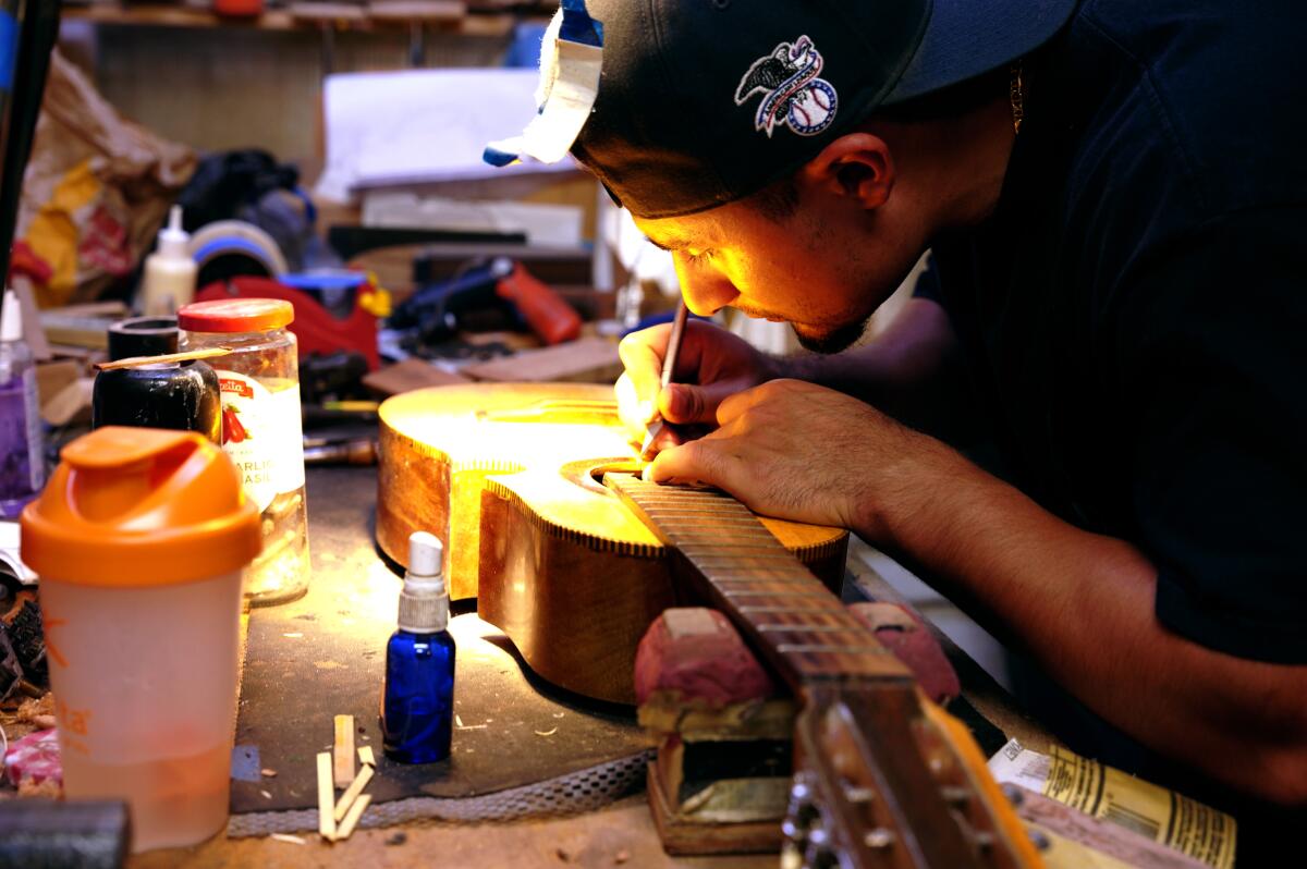 A man hunches over a guitar bathed in light.