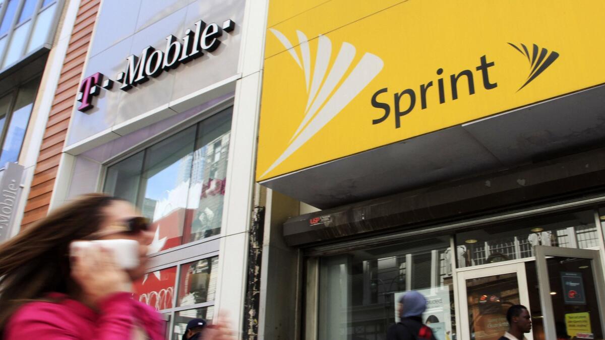 A woman using a cellphone walks past T-Mobile and Sprint stores in New York in 2010.