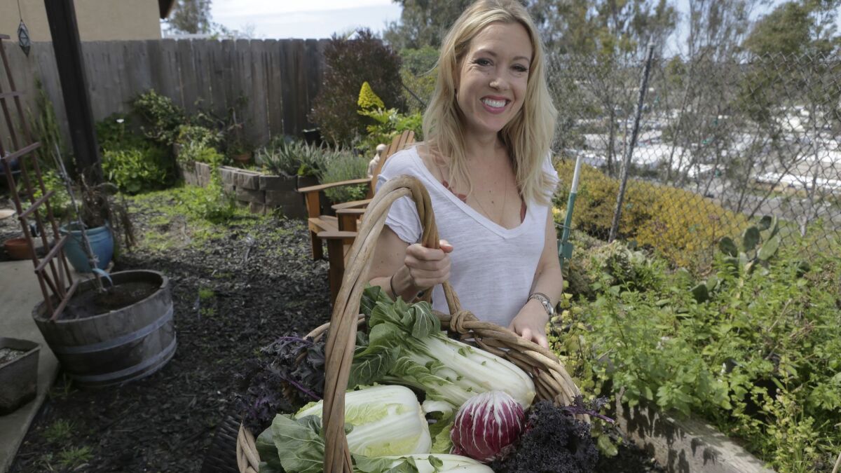 Restaurateur Jessica Waite, with some of the leafy, green vegetables she will be featuring at her new Oceanside restaurant, at her Oceanside backyard garden area Friday. photo by Bill Wechter