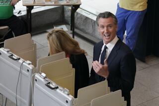 California Gov. Gavin Newsom reacts as he looks up and spots photographers capturing him and first partner Jennifer Siebel Newsom, left voting at a voting center in Sacramento, Calif., Tuesday, Nov. 8, 2022. Newsom is running for reelection against Republican state Sen. Brian Dahle. (AP Photo/Rich Pedroncelli)