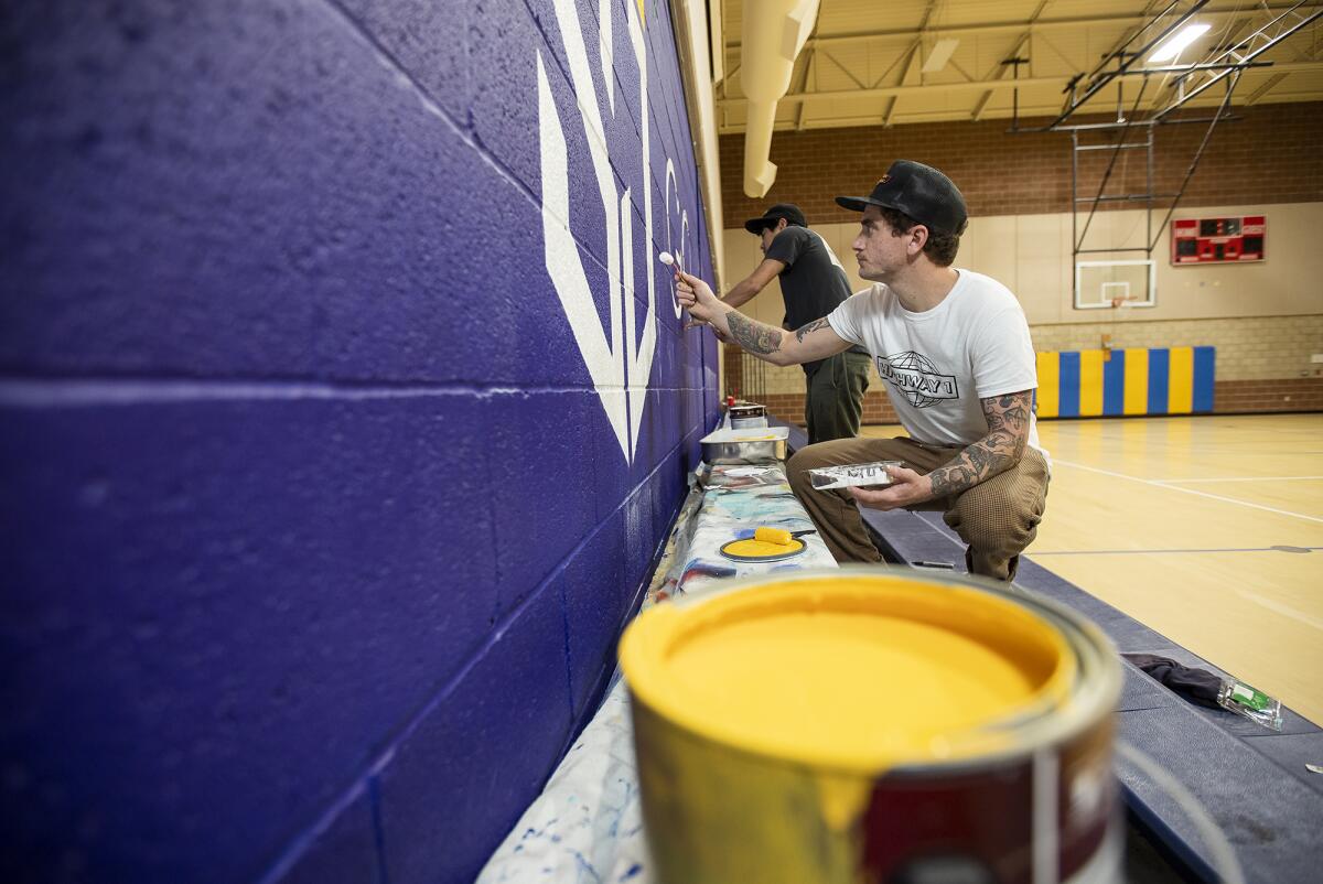 Cody Parole, a Costa Mesa-based artist, and Joe Suzuki work on a mural at St. Joachim Catholic School in Costa Mesa this month.