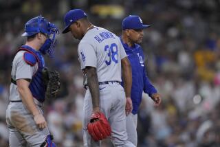 Los Angeles Dodgers manager Dave Roberts, right, takes the ball from relief pitcher Yency Almonte.