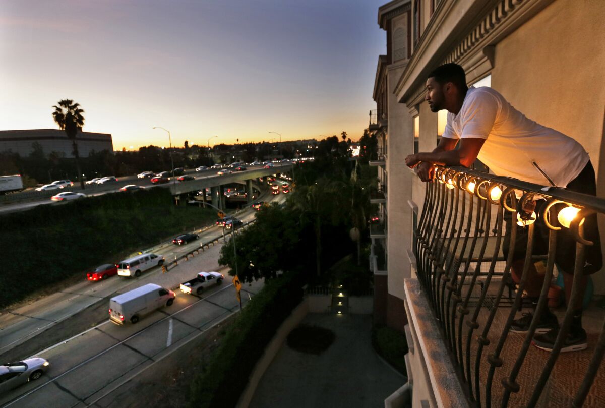 Everett Smith, a renter at the Orsini apartments, looks out from his balcony at rush hour traffic on the 101 and 110 freeway interchange in downtown Los Angeles.