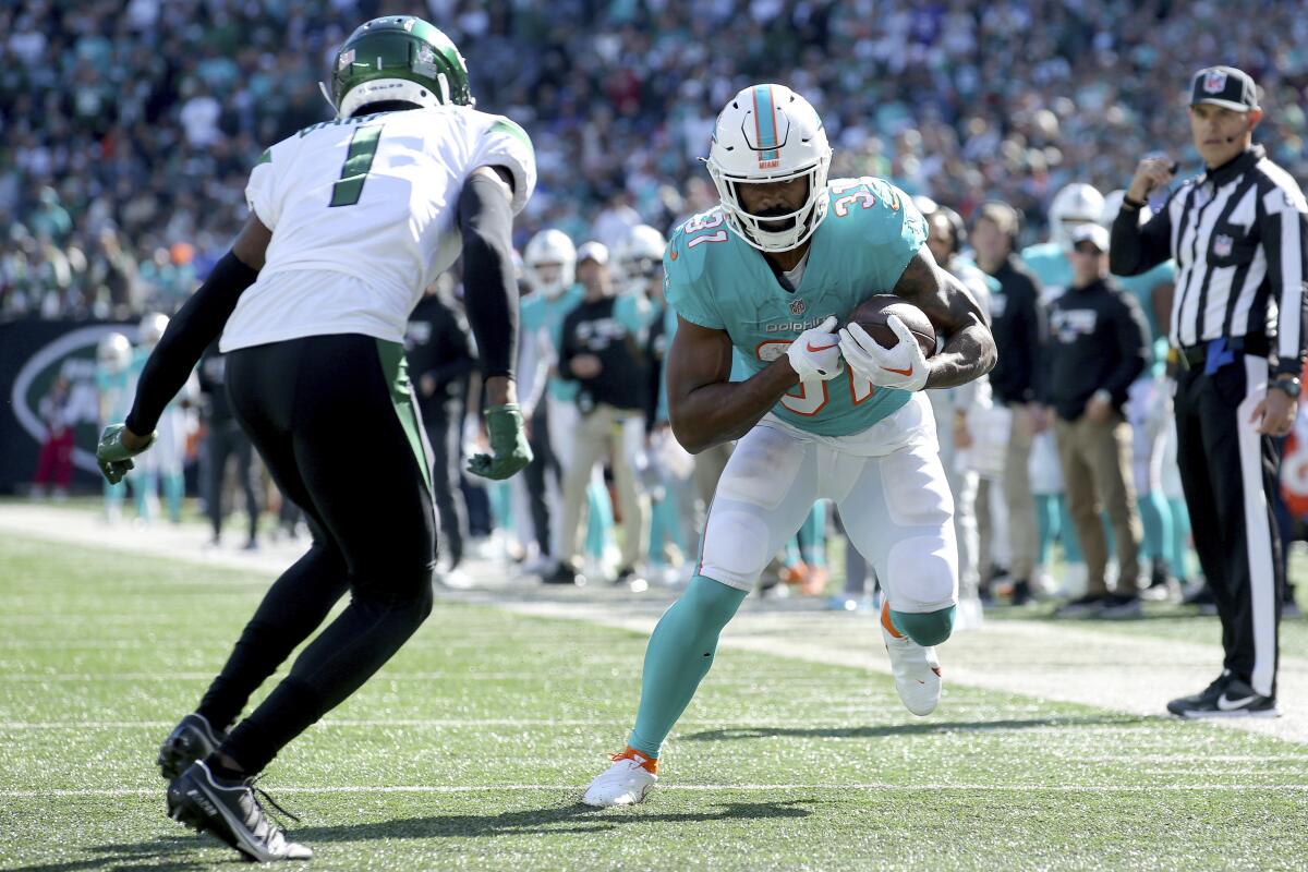Miami Dolphins running back Raheem Mostert in action against New York Jets cornerback Sauce Gardner.